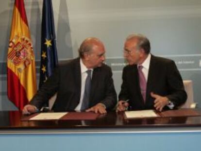 El ministro del Interior, Jorge Fernández Díaz, y el presidente de La Caixa, Isidro Fainé, durante la firma del acuerdo.