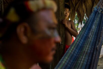 Índios em uma das casas Wajãpi, coberta de palha. Eles se pintam com tinta de urucum e genipapo. Dormem em redes.