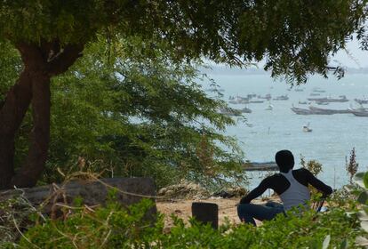 Imagen de un joven a la sombra frente al océano Atlántico, en la playa de Mbour.  