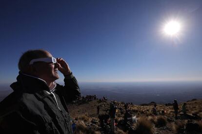 Un hombre mira el sol con anteojos especiales antes del eclipse.