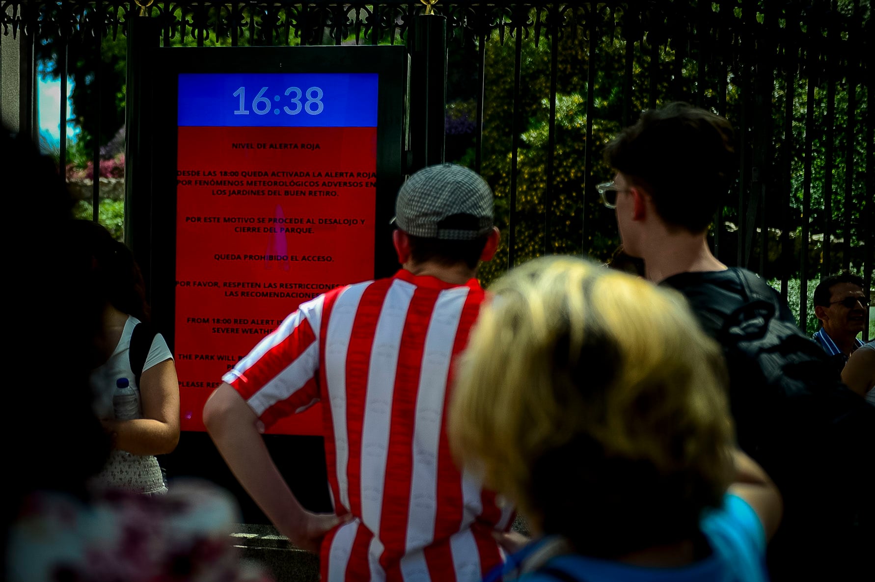 Varias personas consultan la pantalla donde se indica que el parque de El Retiro está cerrado en mayo de 2025. 