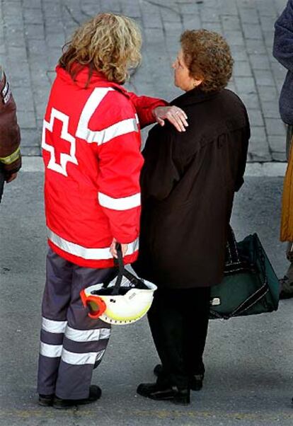 Una asistente de Cruz Roja consuela a una de los afectados.
