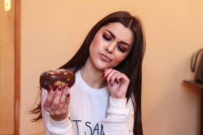 Chica mirando un donut con cara circunspecta