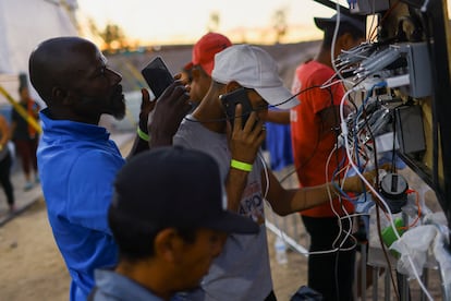 Un grupo de migrantes carga las baterías de sus teléfonos móviles en el refugio habilitado por el INM. 
