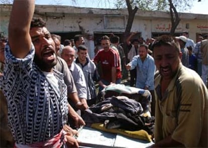 Un grupo de hombres profiere gritos contra EE UU mientras retira un cadáver del lugar del atentado.