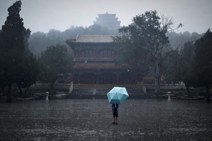 Un joven sostiene un paraguas frente a la Ciudad Prohibida de Pekín (China).