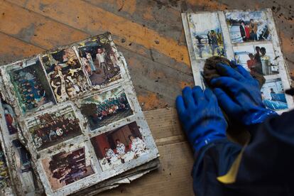 Un voluntario limpia fotografías recuperadas entre los escombros.