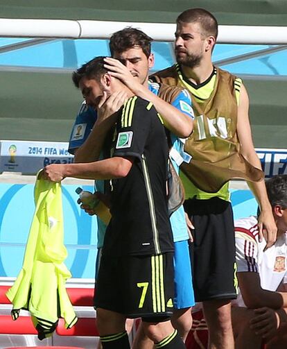 Iker Casillas consuela a David Villa, que se incorpora al banquillo tras haber sido sustituido por Juan Mata.