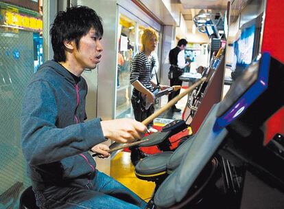 <b>Las recreativas musicales causan furor en Japón desde hace una década. En primer plano, un tokiota aporreando el <i>Drum mania,</i> y al fondo, otro jugando al <i>Guitar freaks.</i></b>