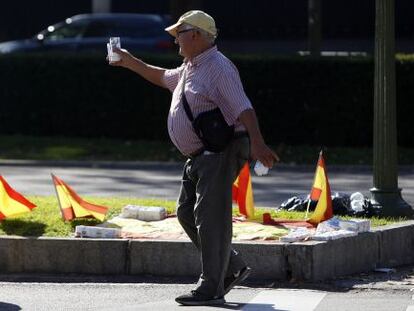 Un hombre ofrece kleenex a los conductores entre banderitas espa&ntilde;olas en el paseo de la Castellana.