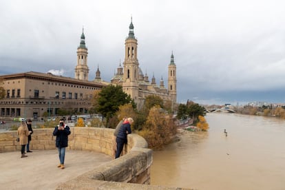 Varios turistas observan el río Ebro a su paso por Zaragoza, el martes. El lunes, la DGT aconsejó a los conductores adelantar el regreso ante la previsión de empeoramiento del tiempo previsto para este miércoles.