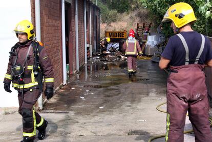 Los bomberos apagan los últimos rescoldos en la fábrica.