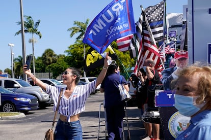 Una joven se toma una foto delante de un centro de votación donde hay seguidores de Trump en Hiealeah, Florida.