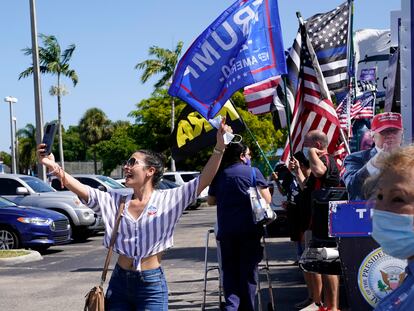 Una joven se toma una foto delante de un centro de votación donde hay seguidores de Trump en Hiealeah, Florida.