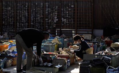 Dos japonesas buscan entre las pertenencias recuperadas entre los escombros y que han sido dispuestos en el gimnasio de un colegio para su identificación.