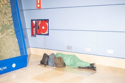 Una persona duerme en los pasillos que conectan la terminal 1 y 2 de Barajas durante la madrugada del lunes. 