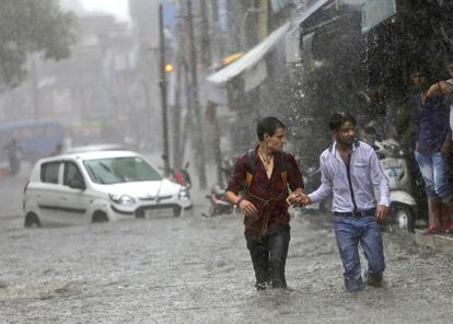 Dos hombres caminan a lo largo de una calle inundada debido a las fuertes lluvias que han afectado a la localidad de Jammu (India).