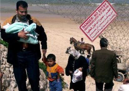 Un palestino con sus dos hijos esquiva el bloqueo israelí de las carreteras de Gaza dando un rodeo por la playa.