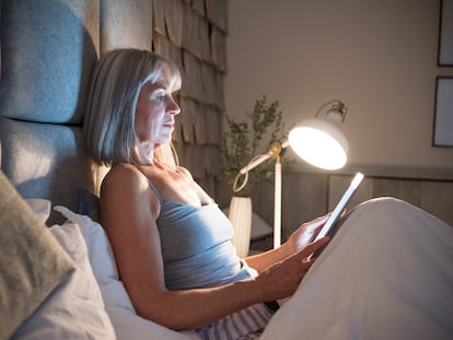 Senior woman sitting in bed at night with tablet