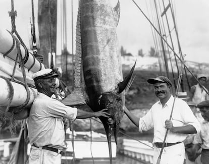 Hemingway con una caña de pescar y un marlín al lado del capitán Joe Russell.