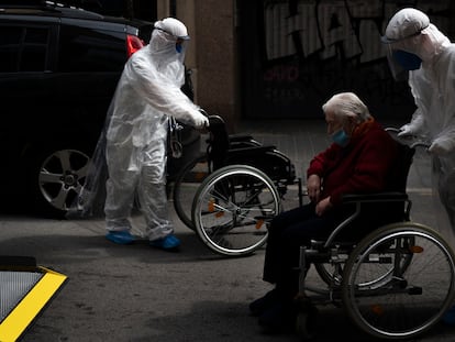 Un voluntario de la ONG Open Arms traslada a un anciano en silla de ruedas a un hospital de Barcelona.