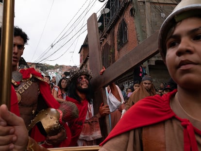 El actor interpretando a Jesús carga la cruz mientras camina hacia El Morro durante la interpretación de las estaciones del vía crucis de la Pasión de Cristo en la zona popular de Petare, Caracas, Venezuela, el 7 de abril de 2023.