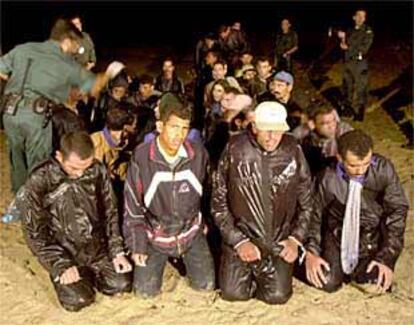 Un grupo de inmigrantes, ayer, en la playa custodiados por la Guadia Civil.