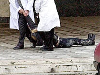 Dos sanitarios arrastran el cadáver de una de las rehenes del <i>comando</i> checheno frente al teatro de Moscú.