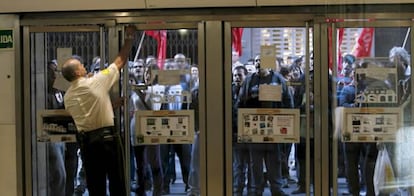 Un guardia de seguridad abre la puerta de la FNAC frente a un piquete, durante la jornada de huelga general contra la reforma laboral y la política económica del Gobierno.