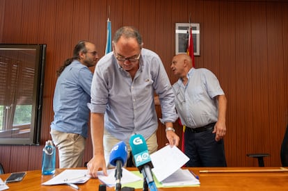 Alcalde saliente y entrante se dan la mano, con el secretario municipal de Touro en primer término.