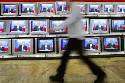 Un hombre camina en Moscú por delante de un escaparate con televisores que muestran la imagen del presidente Vladímir Putin.