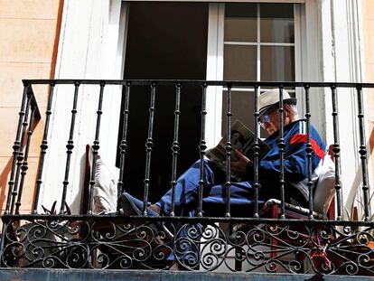 Un hombre lee en un balcón, el Primero de Mayo en Madrid.