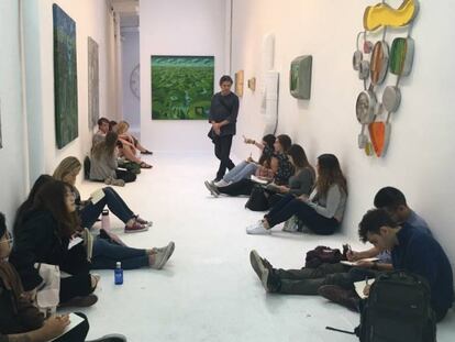 Jordi Gispert, al fondo, en su exposición, con estudiantes de arte. 