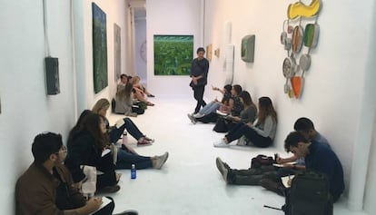 Jordi Gispert, al fons, a la seva exposició, amb estudiants d'art.