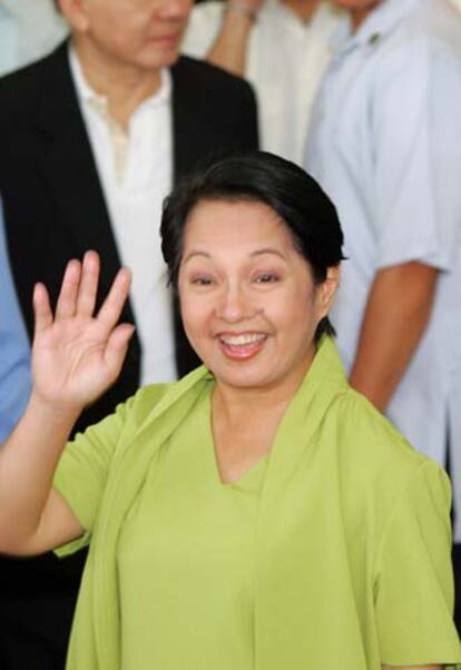 La presidente de Filipinas, Gloria Macapagal, saluda a la gente que esperaba su salida del Centro Médico Saint Luke, justo antes de dirigirse al Palacio Presidencial para firmar la ley que suprime la pena de muerte en el país.