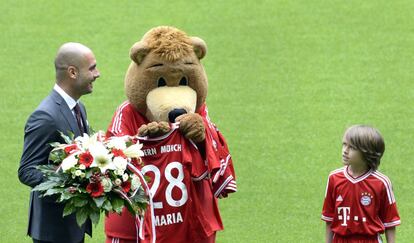 Guardiola, con un ramo de flores en la mano, posa con la mascota del equipo.