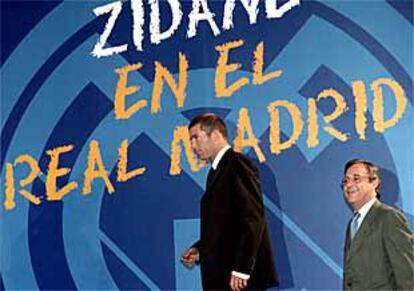 Zidane, seguido por Florentino Pérez, sale al escenario donde fue presentado como jugador del Real Madrid.