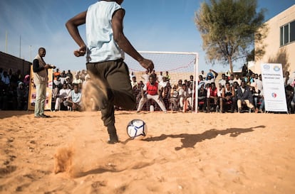 Varios migrantes juegan al fútbol con guardias libios en el centro de detención Tariq Al-Matar, en Trípoli (Libia).