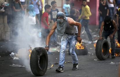 Un palestino rueda un neumático en llamas, durante las protestas en Hebrón (Cisjordania).