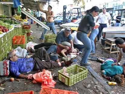 Varios civiles ayudan a los heridos momentos después del atentado en el mercado de Hadera.
