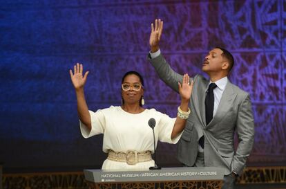 La presentadora Oprah y el actor Will Smith saludan a la multitud.