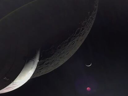 La Artemis 1, a la izquierda, sobrevuela la Luna, en primer término, con la Tierra al fondo. El punto rojo es una aberración de la lente.