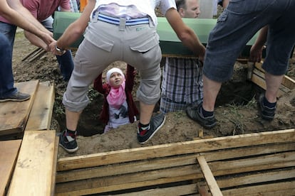 Una niña ayuda a enterrar a una víctima en el centro conmemorativo de Potocari, en las afueras de Srebrenica, 11 de julio de 2013. El funeral de las víctimas exhumadas de fosas comunes e identificadas se celebra cada año con motivo del aniversario de la matanza.