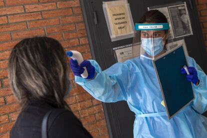 Una sanitaria toma la temperatura a una señora en la entrada del centro de salud Puerto Bonita en Madrid.