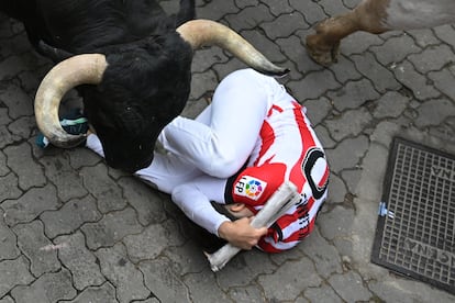 Un mozo se protege al paso de los toros de Victoriano del Río, en el tercer encierro de los Sanfermines.