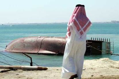 Un hombre observa uno de los botes salvavidas rescatados del barco hundido en Bahrein.