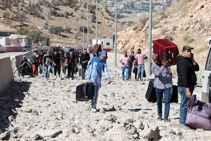 Desplazados libaneses llevan sus pertenencias por la carretera destruida cerca del puesto fronterizo de Masnáa entre Líbano y Siria este viernes.