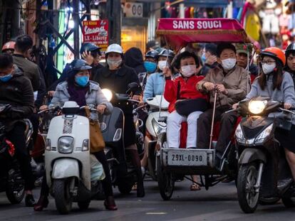 Varias personas con mascarilla circulan en motocicleta por Hanoi, donde se han confirmado tres casos del virus. 