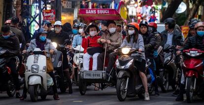 Varias personas con mascarilla circulan en motocicleta por Hanoi, donde se han confirmado tres casos del virus. 