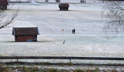 Una pareja camina por un prado cubierto de escarcha en la localidad bávara de Garmisch (Alemania).